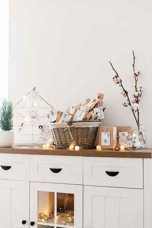 Advent calendar waiting for Christmas. Basket with envelopes with numbers and tasks for children standing on cabinetの写真素材