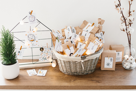 Advent calendar waiting for Christmas. Wire decor note board with christmas cards. Basket with envelopes with numbers and tasks for children standing on cabinetの写真素材