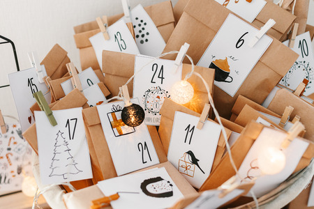 Advent calendar waiting for Christmas. Basket with envelopes with numbers and tasks for children standing on cabinetの写真素材