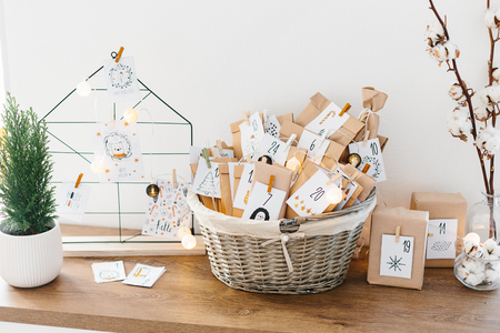 Advent calendar waiting for Christmas. Basket with envelopes with numbers and tasks for children standing on cabinetの写真素材