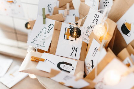 Advent calendar waiting for Christmas. Basket with envelopes with numbers and tasks for children standing on cabinetの写真素材