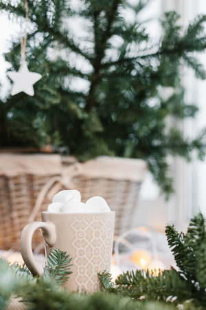 Spruce branches in basket and cup with cacao and marshmallow. Rustic new year christmas decoration at home, scandinavian interiorの写真素材