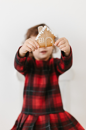 Little girl holding homemade gingerbread cookies house shape. Christmas time. Real estate conceptの写真素材