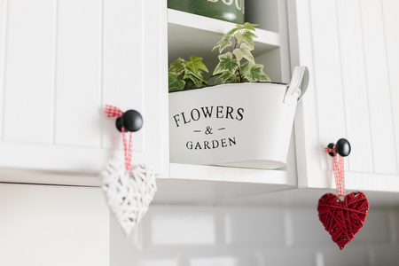 Heart shape decoration hanging on white kitchen cabinets close up kitchen details. Decorate your kitchen with loveの写真素材