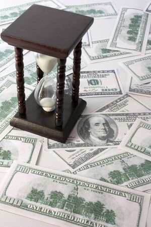 sand-glasses with white sand on hundreds of dollars
