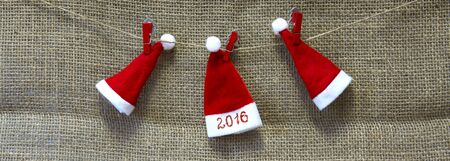 Christmas accessories hanging on  brown cloth  background.Three red  christmas hats isolated on...