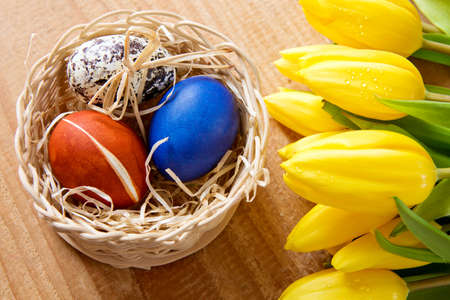 Basket of colorful Easter eggs nestling  and flowers. Easter card.の写真素材