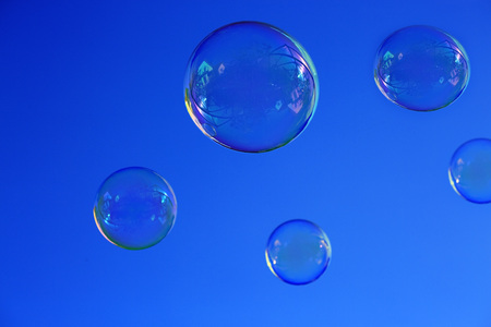 Photo of natural shaped soap bubbles over clear blue sky.の写真素材