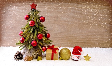 Christmas tree with decoration. Christmas concept with gift and red hat on white snow.