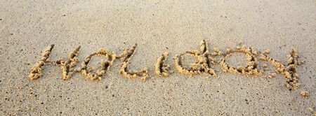 Holiday Written in sand at the beach.の写真素材