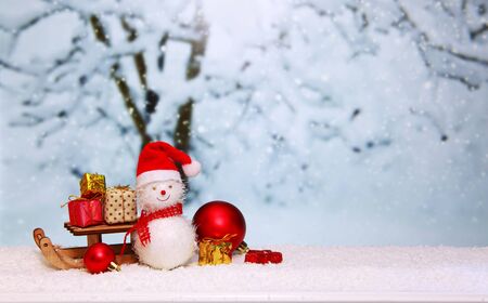 Snowman with Christmas gifts on the sledge isolated on winter background.の写真素材