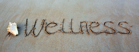 Word Wellness written on the sand near the sea.Vacation concept.の写真素材