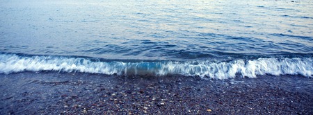 Waves washing over gravel beach, macro shot.