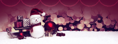 Snowman with Christmas gifts on the sledge isolated on blur background.の写真素材
