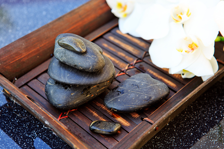 White orchid flower and spa stones with water drops isolated on black background.の写真素材