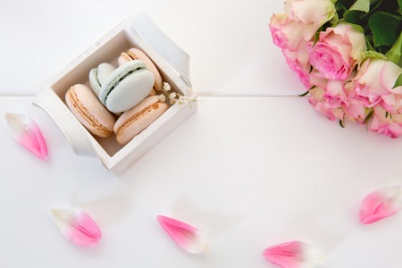 Pink roses and macaron cookies in the basket on white background.の写真素材