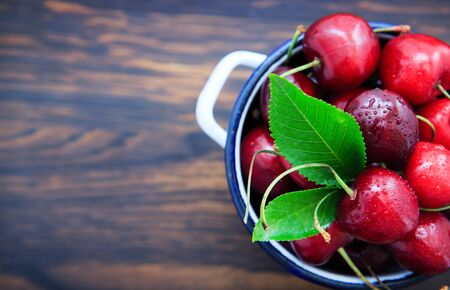 Cherries in the cooking pot on an old wooden background.の写真素材