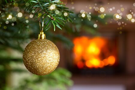 Golden Christmas ball against a stone fireplace. Bokeh holiday light background.の写真素材