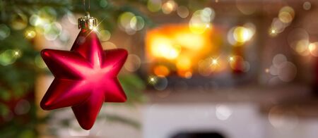 Red Christmas star against a stone fireplace. Bokeh holiday light background.の写真素材
