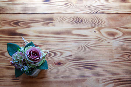Bouquet of pink roses in a basket on brown wooden background.