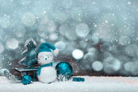 Christmas snowman with gifts on the sledge and snowfall.の写真素材