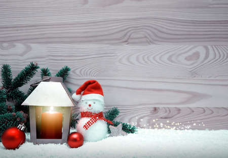 Snowman with Christmas decorations and burning lantern.