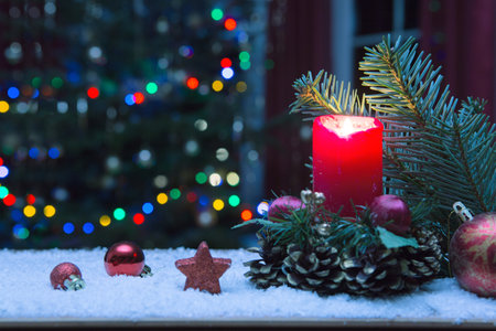 Christmas red candle with decorations and fir tree isolated on lights background.