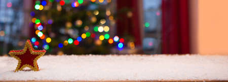 Red Star on white snow isolated on Christmas tree lights background.の写真素材