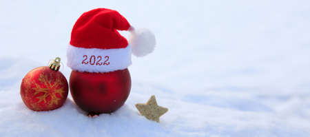 New year 2022 background with red Santa hat and decorations on white snow.の写真素材