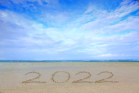 New Year 2022 written at the caribbean sand beach with sea wave .