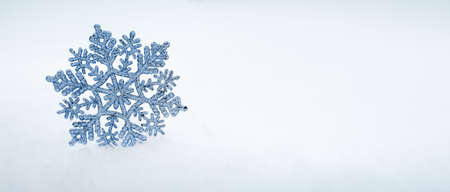 Christmas background with blue snowflake on white snow.