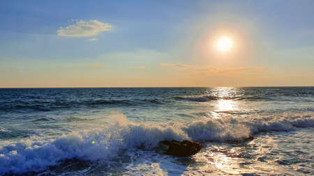 Colorful sunset with large sun under the sea waves.の写真素材