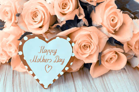 Happy Mothers Day card with yellow roses on wood background.