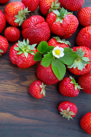 Strawberries and flower on brown wooden background.の写真素材