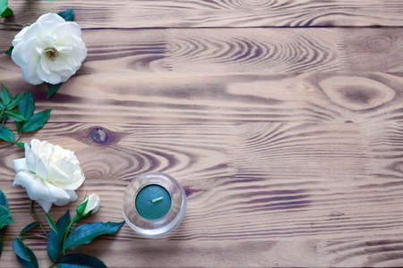Two white roses and candle on brown wooden background.の写真素材