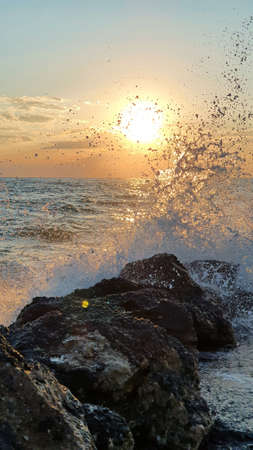 Colorful sunset with large sun under the sea waves.