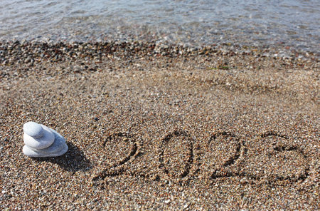 New year 2023 handwritten in the sand surface and spa stones.の写真素材
