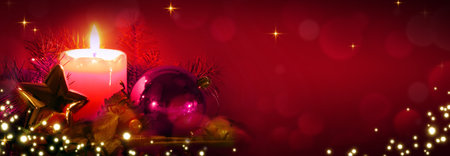 Red Advent candle with Christmas decorations isolated on blur bokeh background.の写真素材
