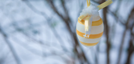A white Easter egg is hanging on a branch of a cherry tree. Easter spring backgroundの写真素材
