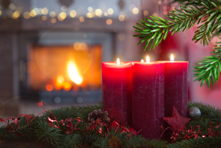 Four burning red Advent candles in a warm interior with fireplace.の写真素材