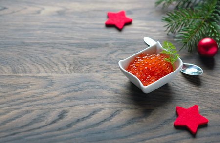 Salmon Red Caviar in bowl and Christmas decorations on wooden background.の写真素材