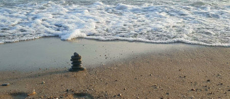 Pyramid stones on the seashore on a sunny day on the blue sea background.の写真素材