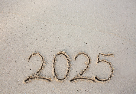 New Year 2025 handwritten in the white sand surface.の写真素材