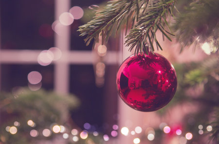 Close up of red Christmas ball on fir tree. Bokeh garlands in the background.の写真素材