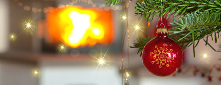 Christmas ball on fir tree branch and blur burning fireplace background.の写真素材