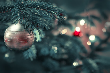 Close up of golden Christmas ball on fir tree. Bokeh garlands in the background.の写真素材