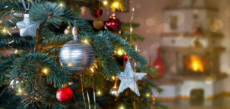 Christmas tree branch with silver decoration and blur burning fireplace background.の写真素材