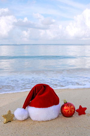 Christmas background with red Santa hat and decorations on Caribbean Beach.の写真素材
