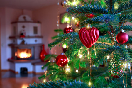 Christmas tree branch with red decoration and blur burning fireplace background.の写真素材