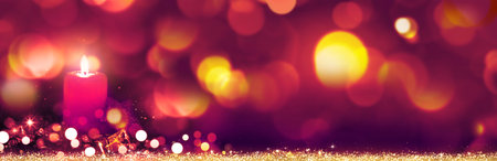 Burning red Advent candle on colorful lights background.の写真素材